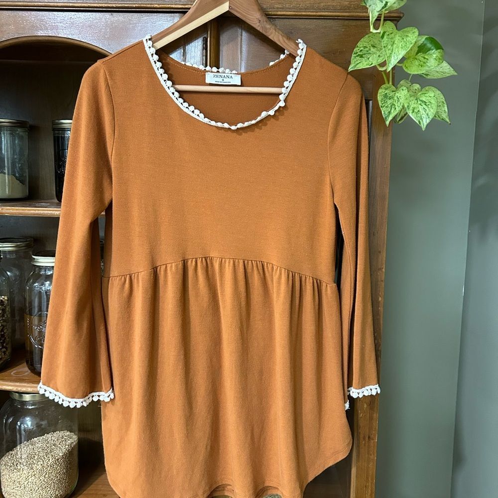 Burnt orange oversized tunic blouse with delicate trim details.
